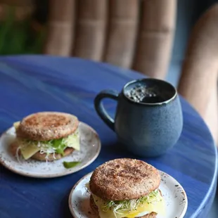 two sandwiches on a table with a cup of coffee