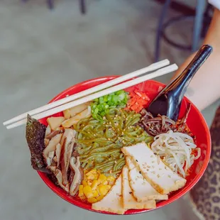 a person holding a bowl of ramen