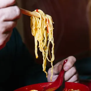 a woman eating ramen with chopsticks