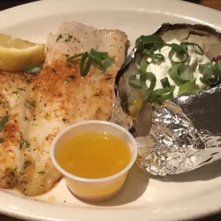 a plate of fish, potatoes, and a baked potato