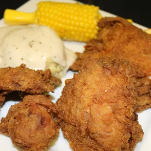a plate of fried chicken, mashed potatoes, and corn on the cob