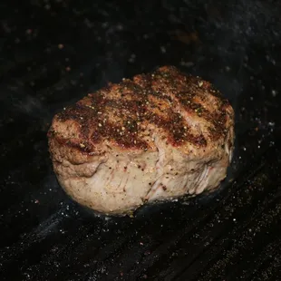 a steak cooking on a grill