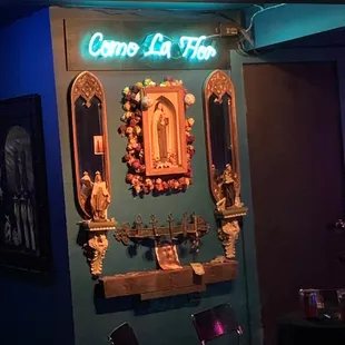 a room with a table, chairs, and a neon sign that reads come la hip