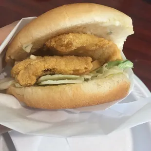 Inside the fish sandwich. Comes with iceberg lettuce, a tomato slice, tartar sauce spread, and two fish patties