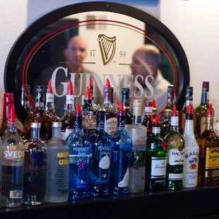 a man in the mirror behind a bar filled with bottles of alcohol