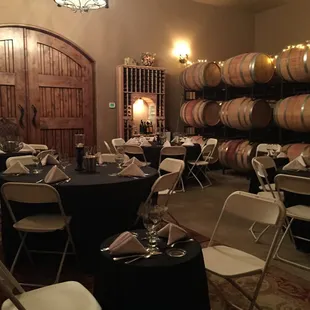 tables and chairs with wine barrels in the background