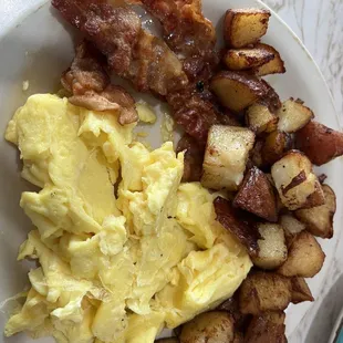 a plate of eggs, potatoes and bacon