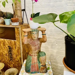 a clay statue of a woman holding a potted plant