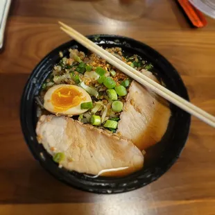 a bowl of soup with chopsticks