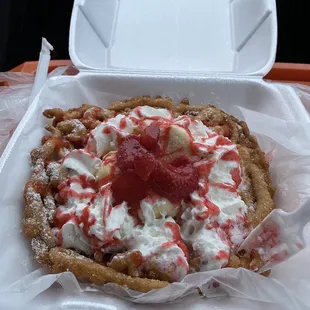 Funnel cake with ice cream and strawberries.