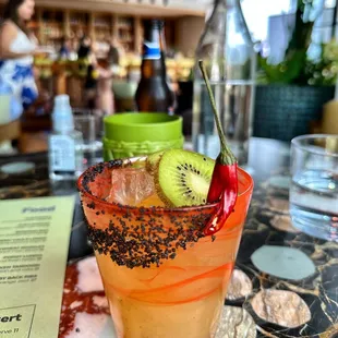 a cocktail with kiwi, orange juice, and black sprinkles