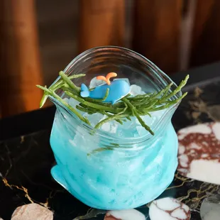 a blue drink in a glass on a table