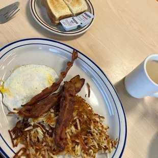 a breakfast of eggs, bacon, hash browns and toast