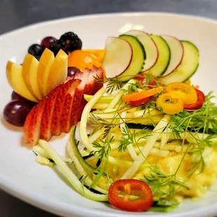 Garden Brie Scramble with soft scrambled eggs, fresh vegetables, fruit, and microgreens