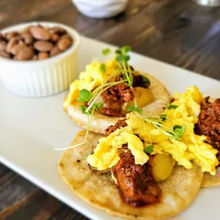 Carne Adovada Tacos with eggs, corn tortillas, red chile, and potatoes. Includes beans.