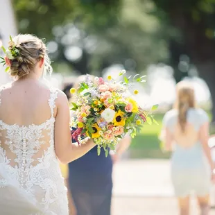 Gorgeous shades of color using standard roses, spray roses, large sunflowers, billy balls, gomphrena, fever few, italian ruscus and more