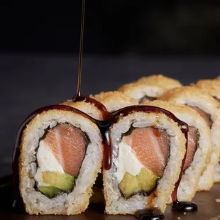 a piece of sushi being drizzled with sauce