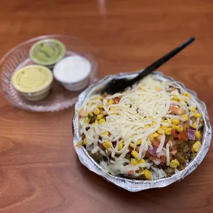 a bowl of mexican food and a container of dips