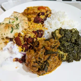 Plate of various takeout items. Bhindi Masala, Salmon Tikka Masala, Saag Paneer, Boneless Chicken Biryani, Garlic Naan, Butter Chicken.