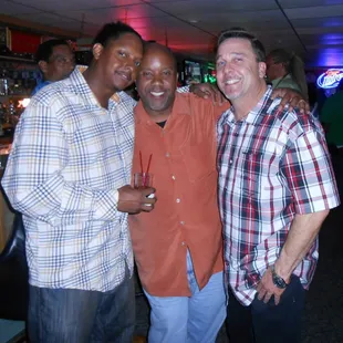 three men standing together in a bar