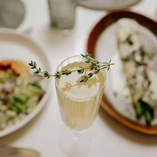 a glass of champagne with a sprig of thyme