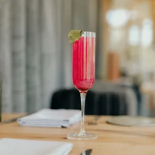 a pink cocktail in a tall glass on a wooden table