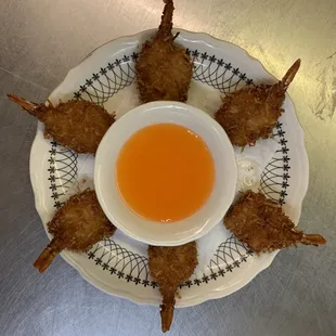 a plate of fried shrimp skewers with a dipping sauce