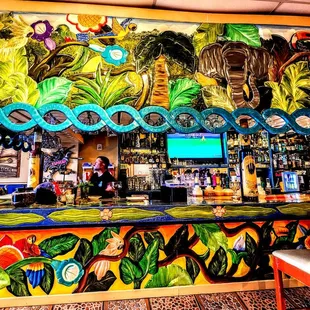 a bar with a colorful mural on the wall