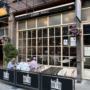 two people sleeping on a bench in front of a building