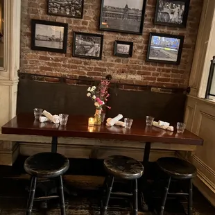 a table with four stools in front of a brick wall