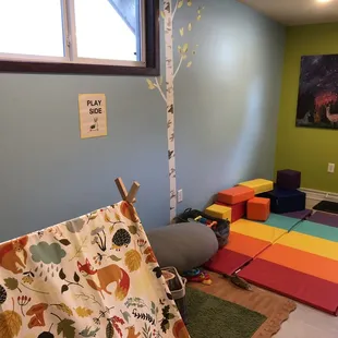 a playroom with a teepee and colorful rugs