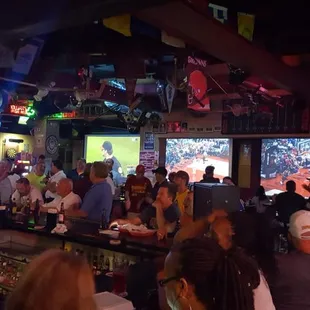 people sitting at a bar watching televisions