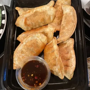 a tray of empanadas with dipping sauce