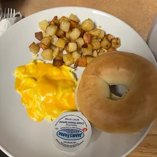 Breakfast platter. One egg with potatoes and a bagel with cream cheese.