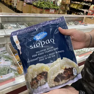 a hand holding a bag of frozen meat