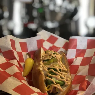 a hot dog in a basket with a pickle