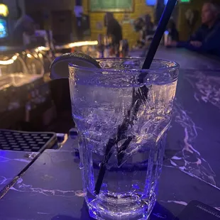 a glass of water with ice and a straw