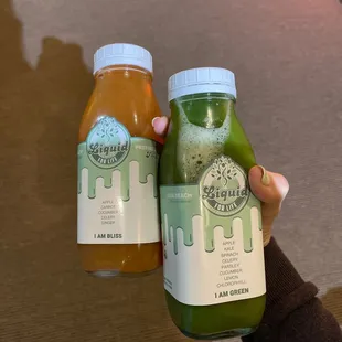 a hand holding two bottles of juice