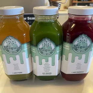 three bottles of juice on a counter