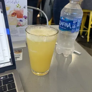 a glass of orange juice next to a bottle of water