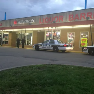 two police cars parked in front of a liquor barrel