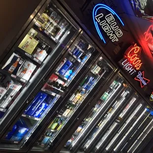 a row of beer coolers with neon signs