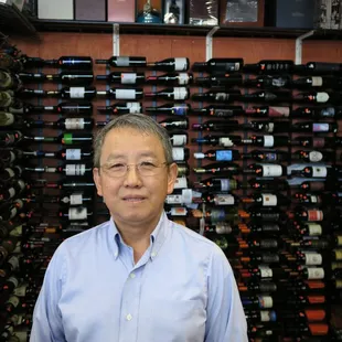 a man standing in front of a wall of wine bottles