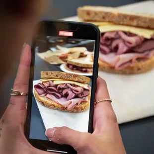 a person taking a picture of a sandwich