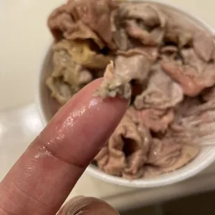 a hand holding a fork and a bowl of food