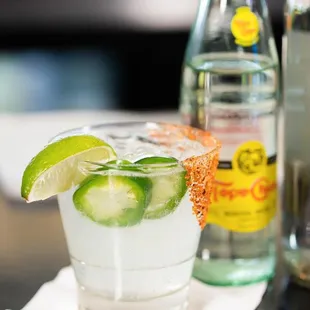 a margarita with lime and a slice of cucumber