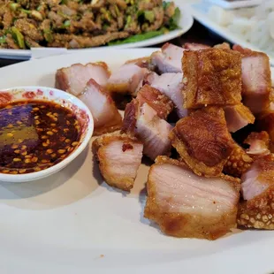 a plate of meat and a bowl of sauce