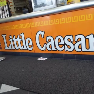 a man walking past a little caesars sign