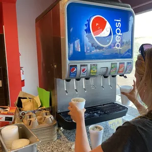 a woman at a counter with a soda machine