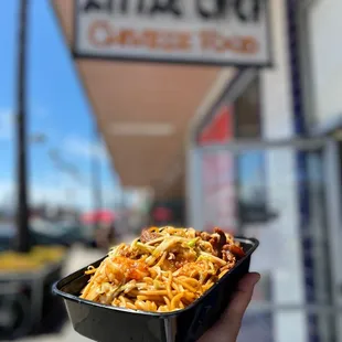 a hand holding a container of noodles